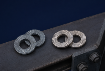 Two Wedge Washer pairs, one mild steel with zinc-flake finish and one stainless steel, resting on a dark steel surface.